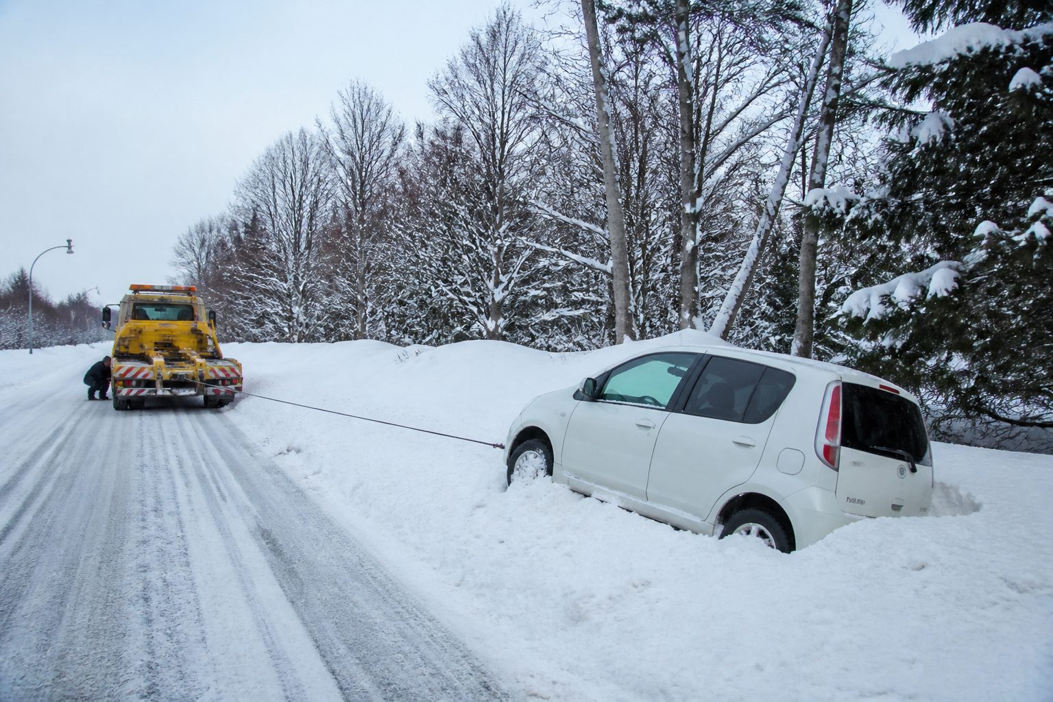 雪に埋まった車をレッカーで救出する様子